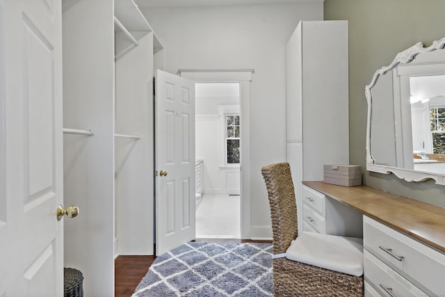 spacious closet featuring dark wood-type flooring and built in desk