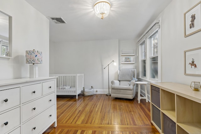 bedroom with multiple windows, a nursery area, and light wood-type flooring