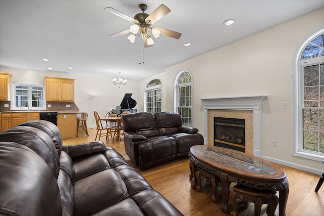 living room with ceiling fan with notable chandelier, light hardwood / wood-style floors, a wealth of natural light, and sink