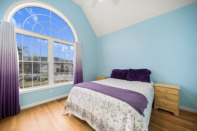 bedroom featuring multiple windows, ceiling fan, hardwood / wood-style floors, and lofted ceiling