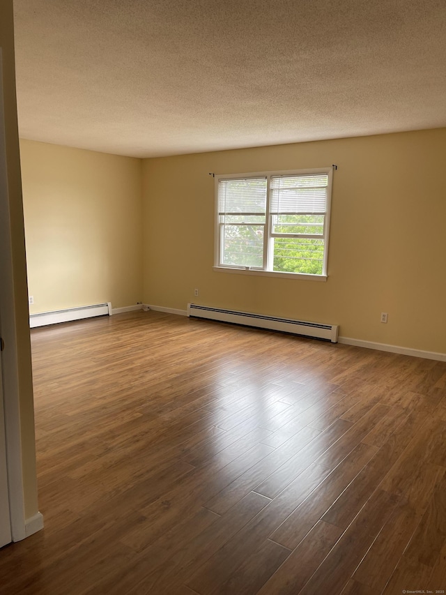 spare room featuring hardwood / wood-style flooring, a textured ceiling, and a baseboard heating unit