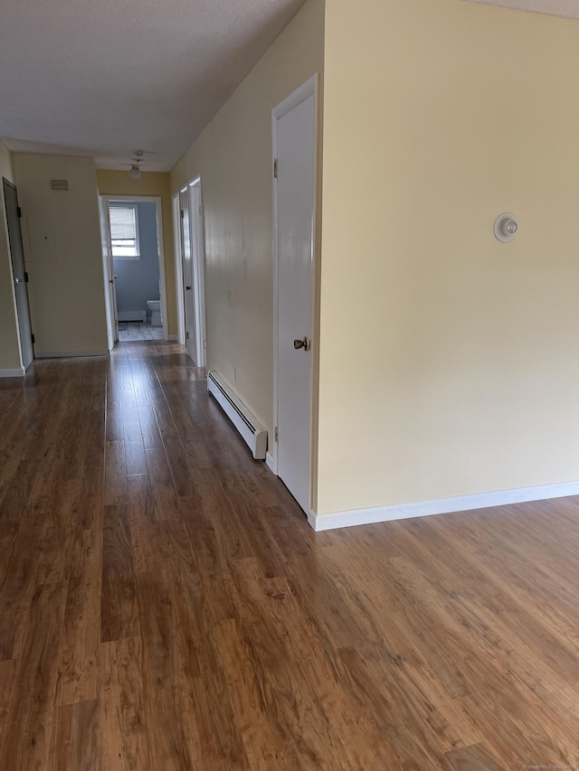 hallway with dark hardwood / wood-style flooring and baseboard heating