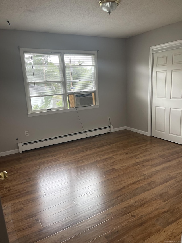 unfurnished room with dark hardwood / wood-style floors, cooling unit, a textured ceiling, and a baseboard radiator