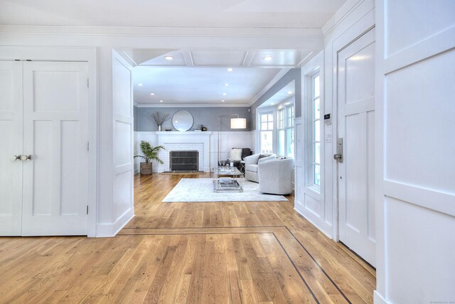 interior space with ornamental molding, a fireplace, and light hardwood / wood-style flooring