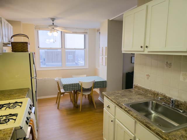 kitchen with white stove, white cabinetry, decorative backsplash, light wood-type flooring, and sink