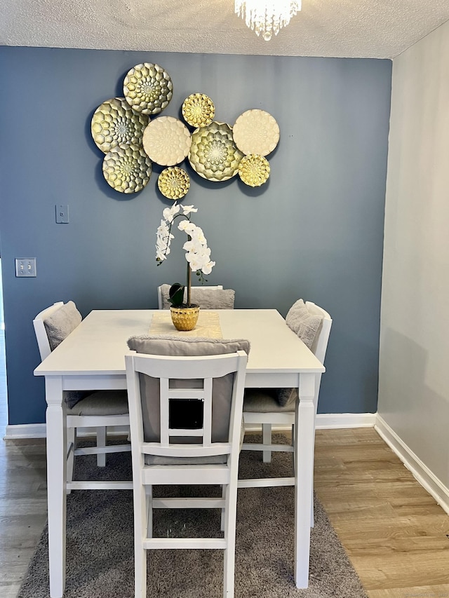 dining space with hardwood / wood-style flooring and a textured ceiling