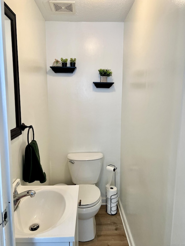 bathroom with hardwood / wood-style flooring, vanity, a textured ceiling, and toilet