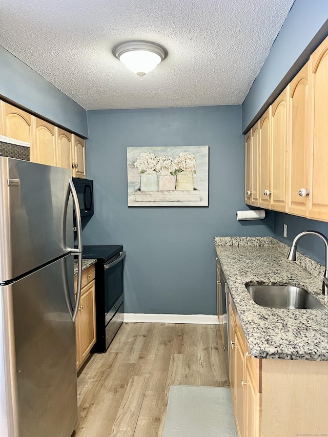 kitchen featuring appliances with stainless steel finishes, sink, light brown cabinetry, and a textured ceiling