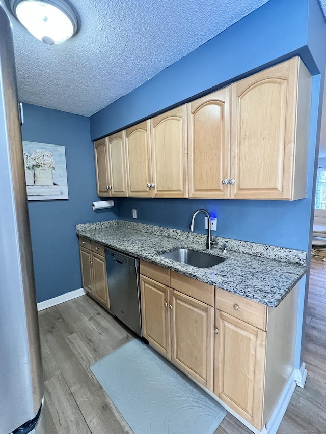 kitchen with light brown cabinetry, wood-type flooring, sink, stainless steel appliances, and a textured ceiling