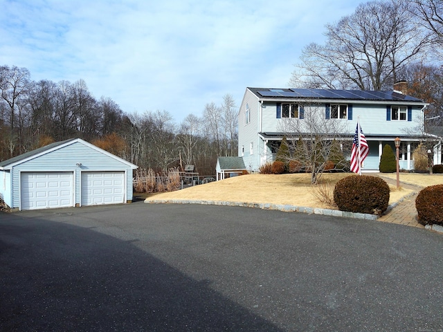 view of front property with a garage, an outbuilding, and solar panels