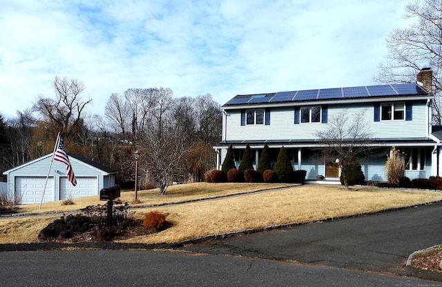 view of front of house featuring an outbuilding, a front lawn, solar panels, and a garage