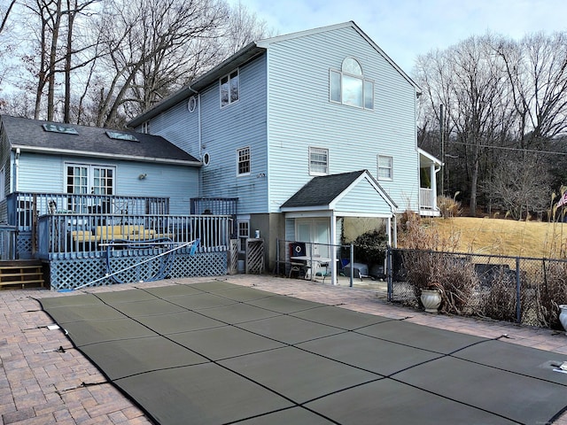 back of house with a wooden deck and a patio