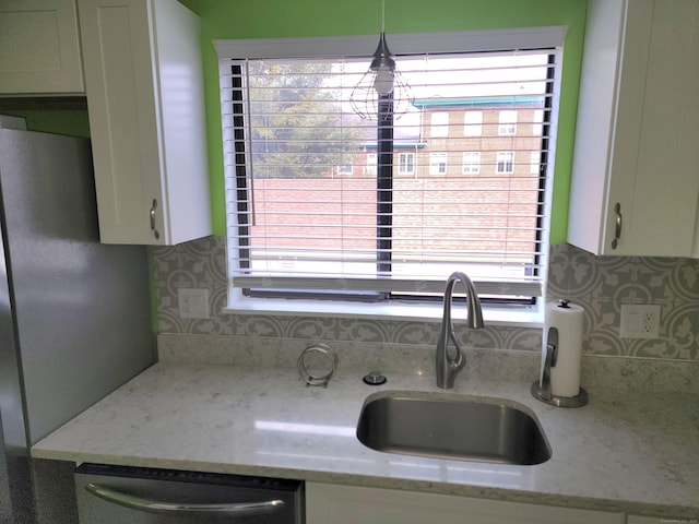 kitchen featuring decorative backsplash, light stone counters, stainless steel appliances, sink, and white cabinetry