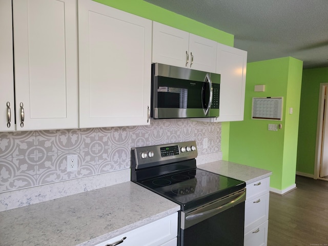 kitchen featuring tasteful backsplash, light stone counters, a textured ceiling, white cabinets, and appliances with stainless steel finishes