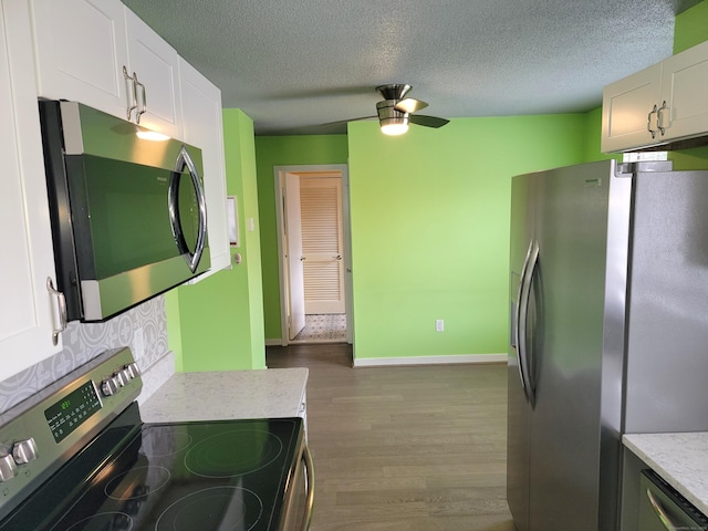 kitchen featuring ceiling fan, hardwood / wood-style floors, a textured ceiling, white cabinets, and appliances with stainless steel finishes