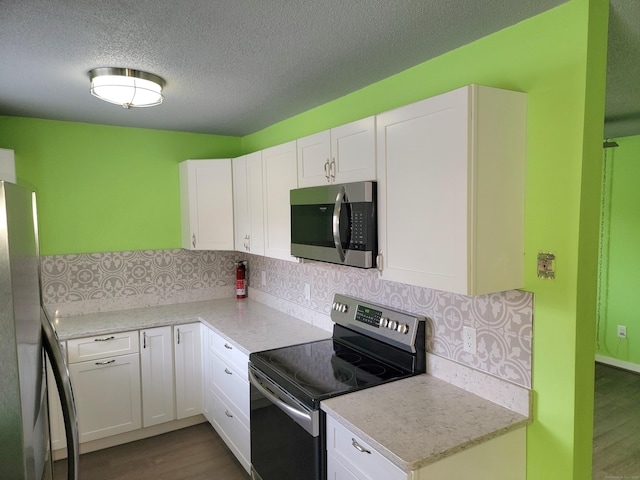 kitchen featuring decorative backsplash, a textured ceiling, stainless steel appliances, and white cabinetry