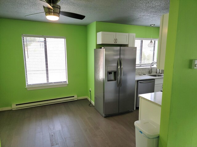 kitchen with sink, stainless steel appliances, a baseboard radiator, pendant lighting, and white cabinets