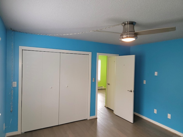 unfurnished bedroom with a textured ceiling, baseboard heating, ceiling fan, wood-type flooring, and a closet