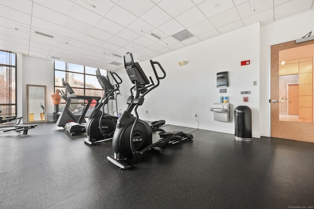 exercise room featuring a paneled ceiling and a wall of windows