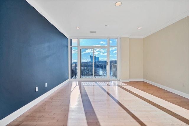 spare room with ornamental molding, light hardwood / wood-style floors, and a wall of windows