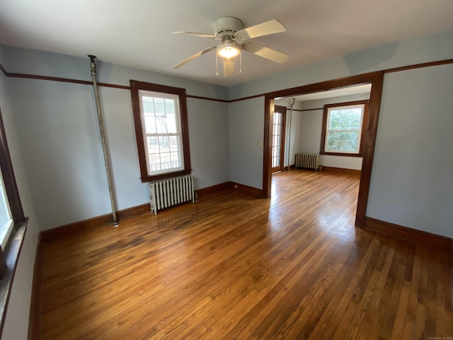 unfurnished room featuring plenty of natural light, wood-type flooring, and radiator