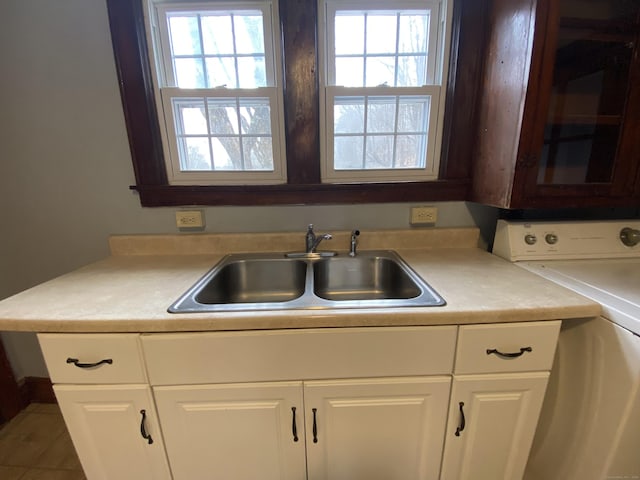 kitchen featuring white cabinets, washer / dryer, and sink