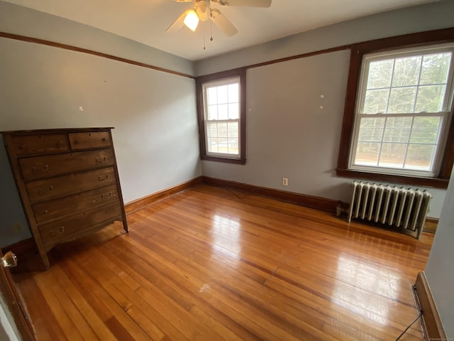 unfurnished bedroom featuring radiator, ceiling fan, and light wood-type flooring