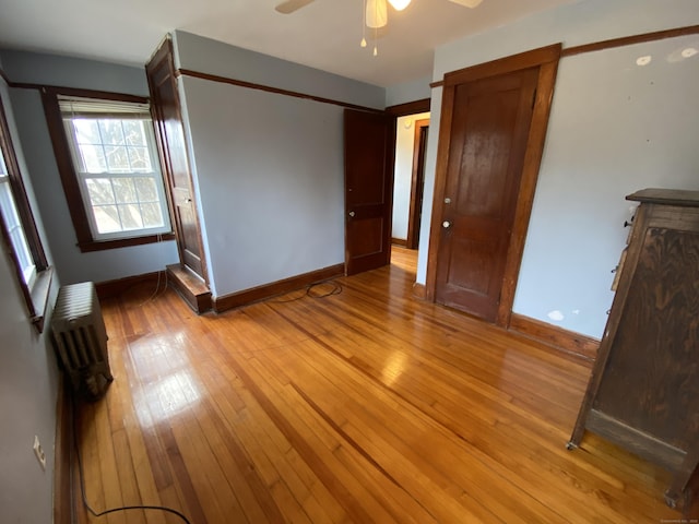 unfurnished bedroom with radiator, ceiling fan, and light wood-type flooring