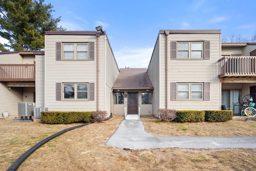 view of front of home with a front lawn, cooling unit, and a balcony