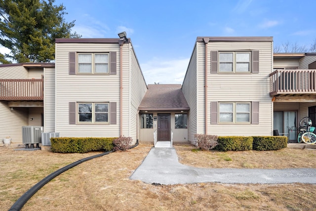 view of front of home with a front lawn, cooling unit, and a balcony