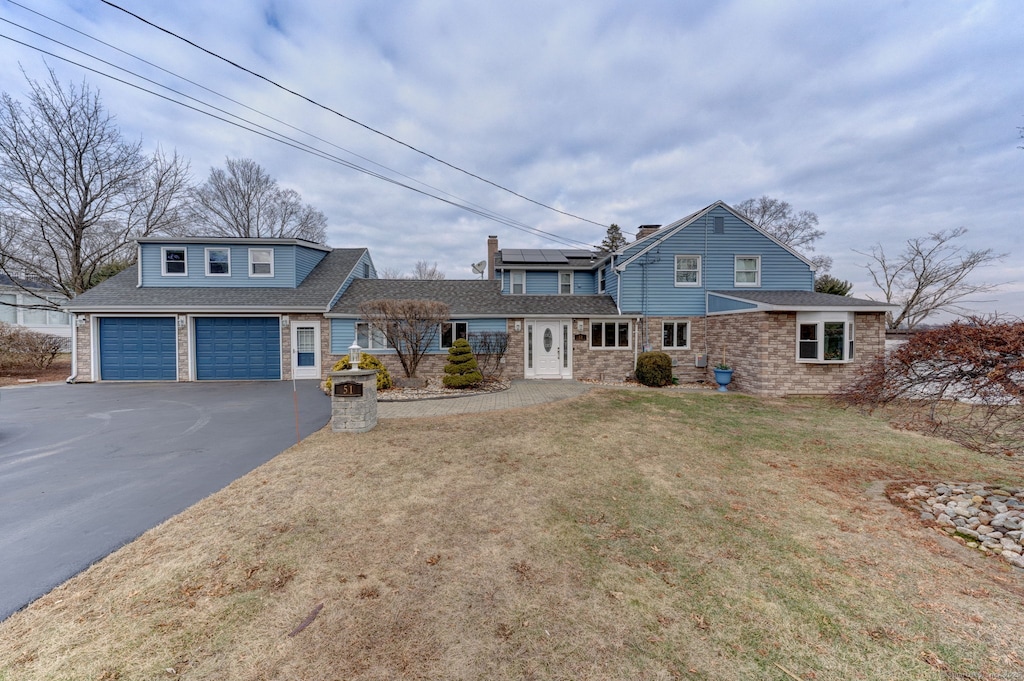 view of front property featuring a front yard and solar panels