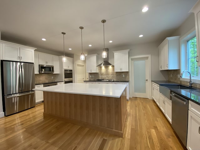 kitchen featuring white cabinetry, appliances with stainless steel finishes, sink, and wall chimney range hood