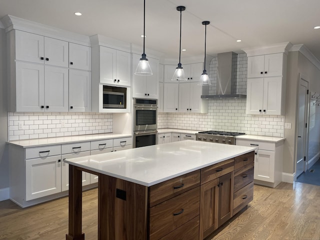 kitchen featuring stainless steel appliances, white cabinetry, and wall chimney range hood