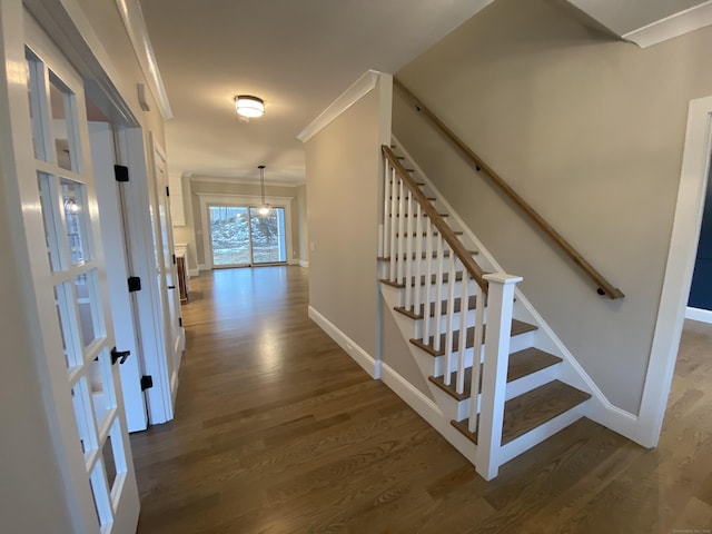 corridor featuring crown molding, dark hardwood / wood-style flooring, and a chandelier