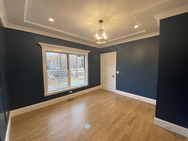 empty room with ornamental molding, light hardwood / wood-style floors, and a chandelier