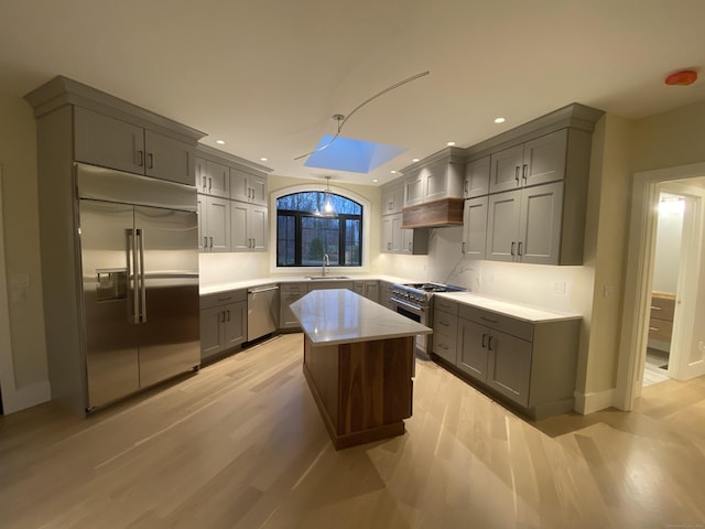 kitchen with sink, gray cabinetry, a center island, high quality appliances, and custom range hood