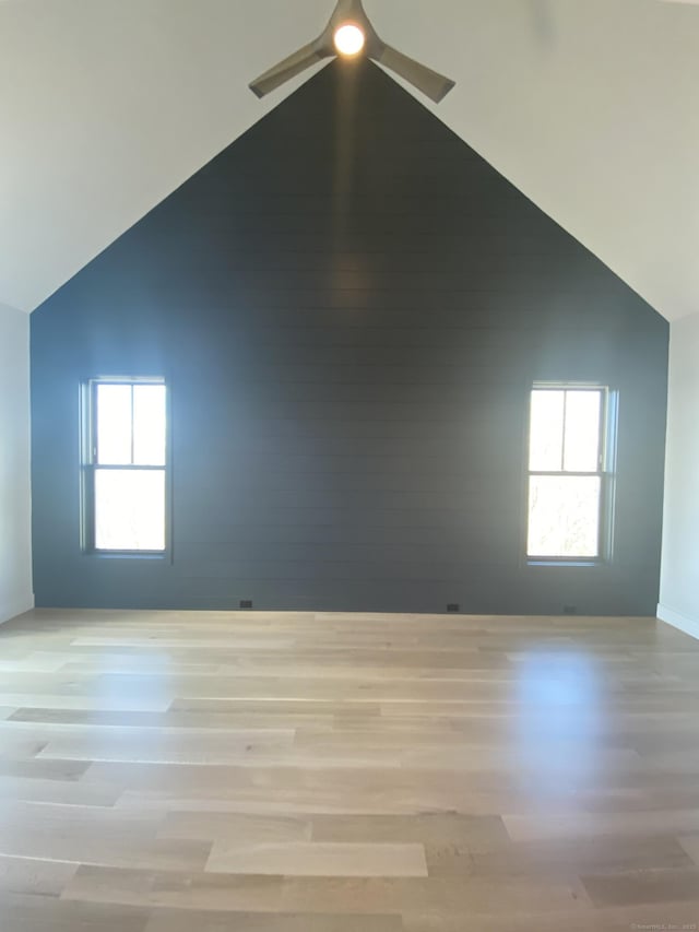 unfurnished room featuring lofted ceiling, a wealth of natural light, ceiling fan, and light hardwood / wood-style flooring