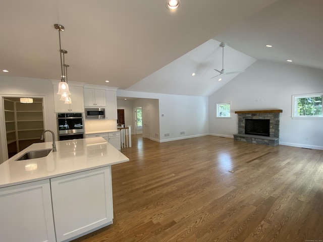 kitchen featuring white cabinetry, stainless steel microwave, sink, and hanging light fixtures