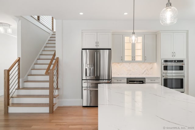 kitchen with decorative light fixtures, beverage cooler, white cabinets, light stone counters, and stainless steel appliances