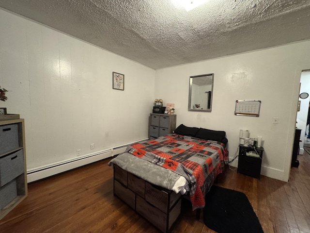 bedroom featuring dark wood-type flooring, a textured ceiling, and a baseboard heating unit