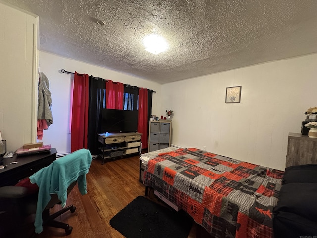 bedroom with dark hardwood / wood-style floors and a textured ceiling