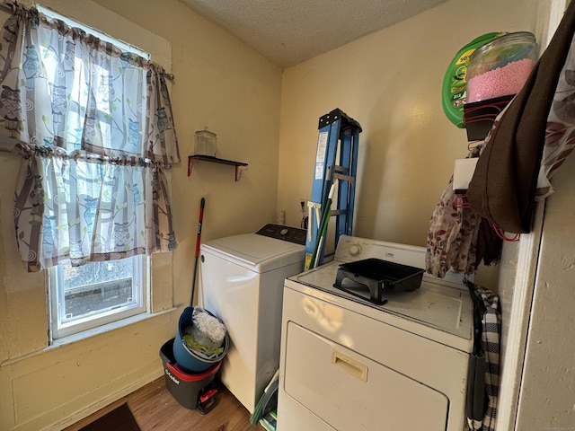 clothes washing area featuring independent washer and dryer, wood-type flooring, and a textured ceiling