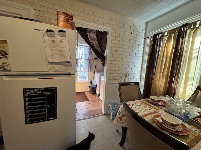 interior space with white fridge, a textured ceiling, and brick wall