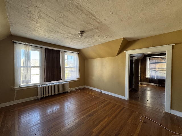 additional living space featuring radiator heating unit, dark hardwood / wood-style floors, vaulted ceiling, and a textured ceiling