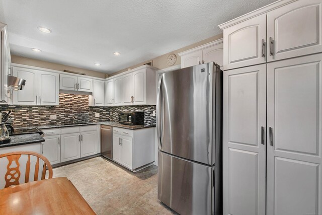 kitchen with stainless steel appliances, decorative backsplash, white cabinetry, and sink