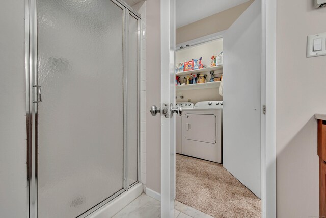 bathroom with washing machine and dryer and a shower with door