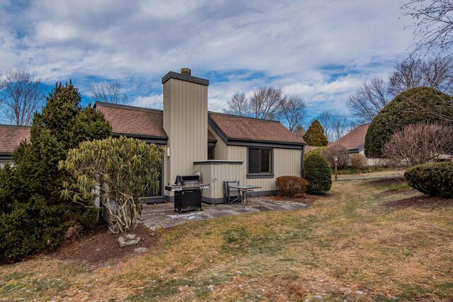 back of property with a lawn and a patio