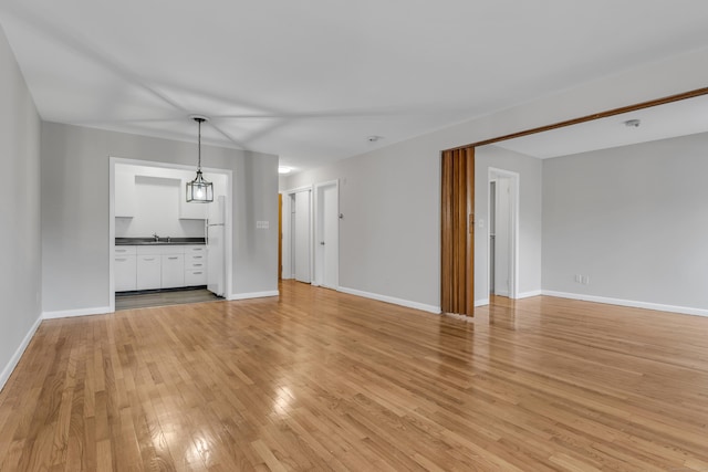 unfurnished living room with sink and light hardwood / wood-style floors