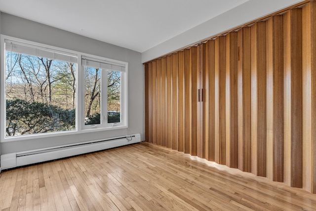 empty room featuring a baseboard heating unit and hardwood / wood-style floors