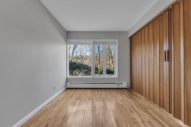 spare room featuring baseboard heating and light wood-type flooring